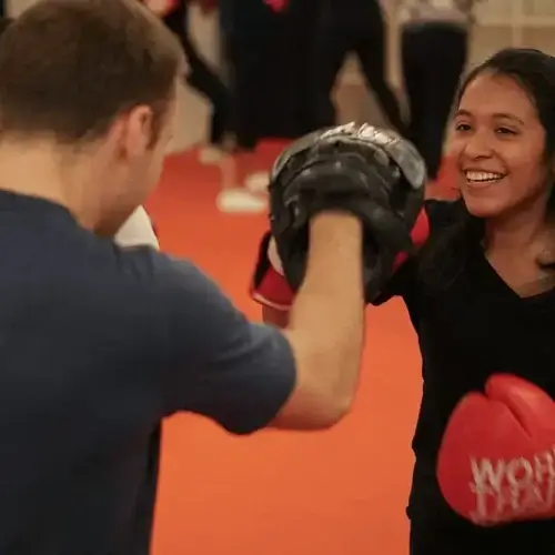 Young girl while sparring with trainer and learning boxing skills