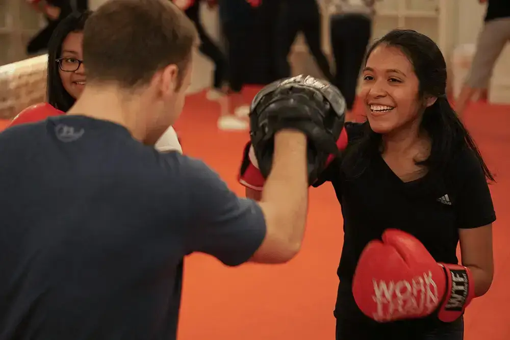 Young girl while sparring with trainer and learning boxing skills