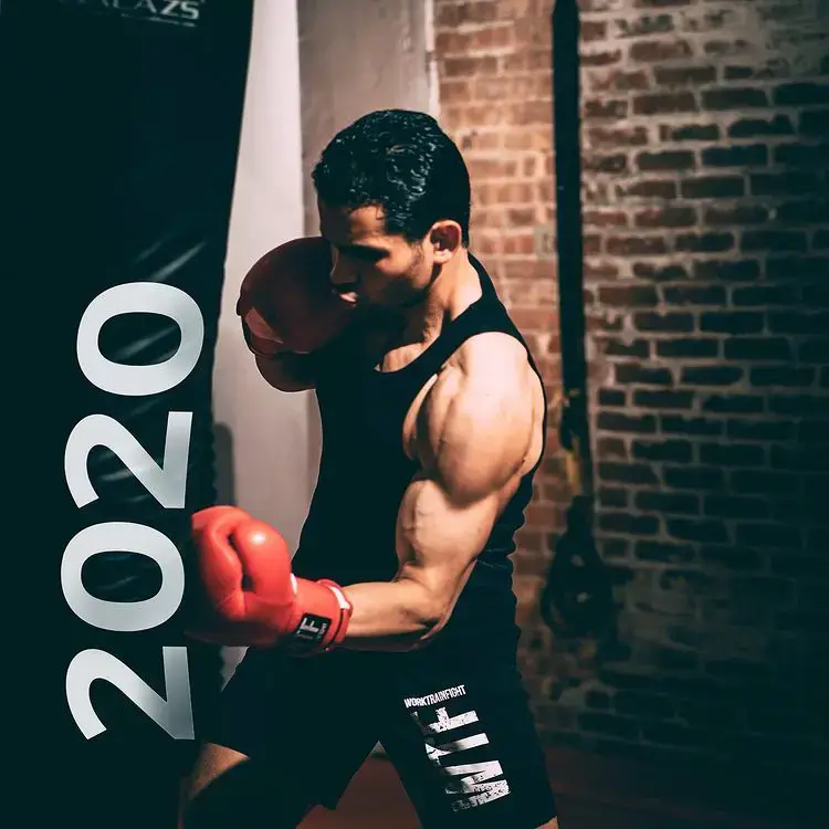 Experienced boxing trainer punching boxing bag